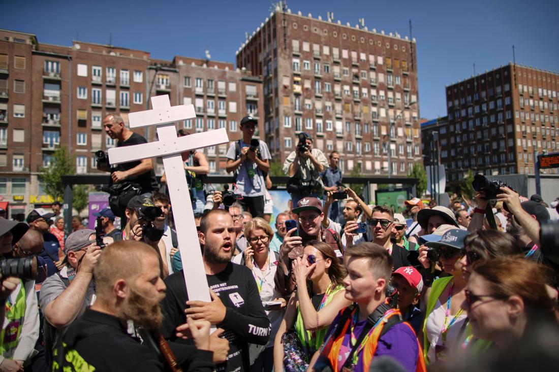 Menschen mit einem Kreuz und religiösen Büchern laufen zwischen den Teilnehmern des Pride-Marsches in Budapest.