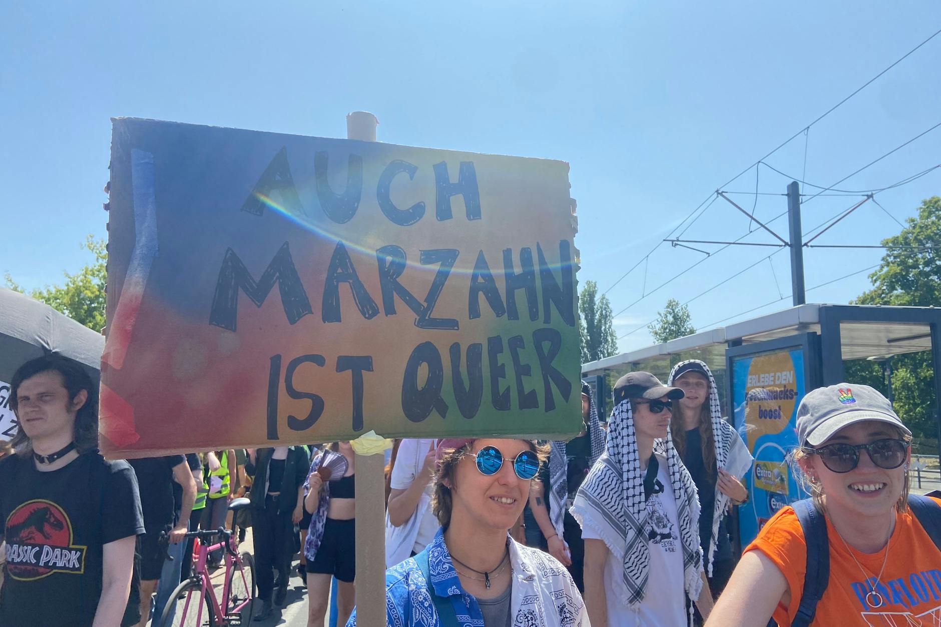 Auf der Pride Parade in Marzahn hält eine Teilnehmerin ein Schild mit der Aufschrift „Auch Marzahn ist queer“ in die Höhe