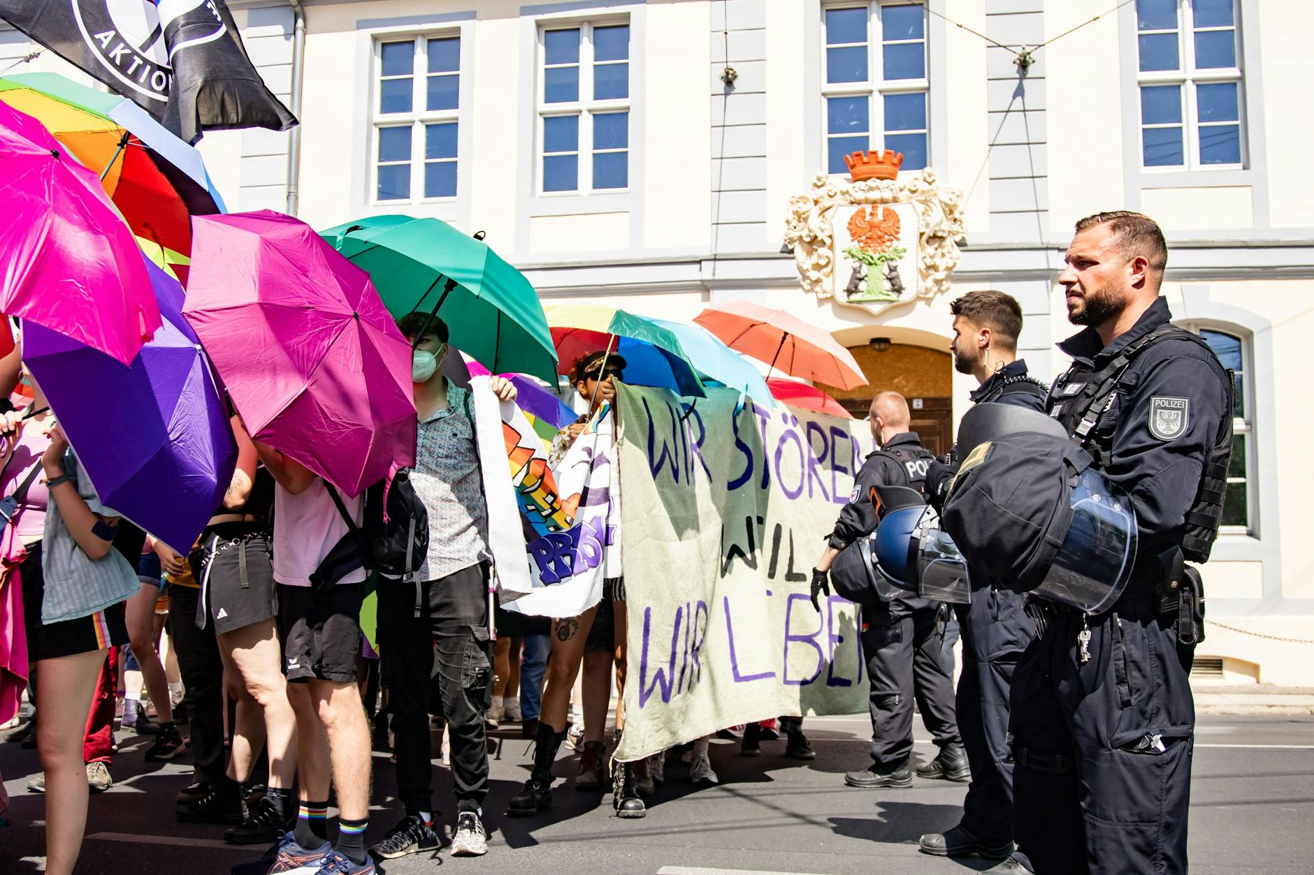 CSD-Teilnehmer blockieren die Sicht vom AfD-Sommerfest auf den Umzug mit Regenschirmen. Die Polizei trennte die beiden Lager konsequent.