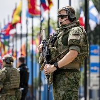 Ein Soldat mit einem Maschinengewehr vor Fahnen.