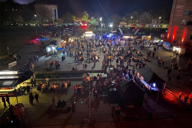 Beim Feierabendmarkt auf der Zeche Ewald in Herten stehen Besucher und diverse Stände auf dem beleuchteten Doncasterplatz.