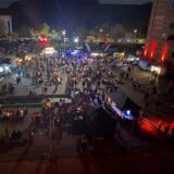 Beim Feierabendmarkt auf der Zeche Ewald in Herten stehen Besucher und diverse Stände auf dem beleuchteten Doncasterplatz.