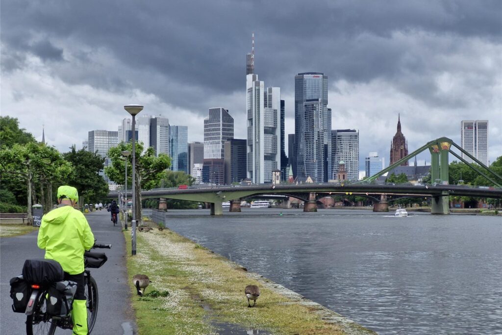 Blick vom Mainufer auf die Skyline von Frankfurt – ein Kontrast aus historischer Uferbebauung und moderner Hochhausarchitektur.