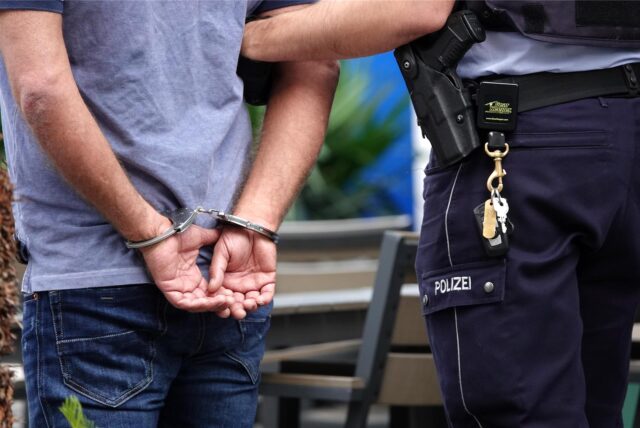 Ein Mann in Handschellen mit einem Polizisten
