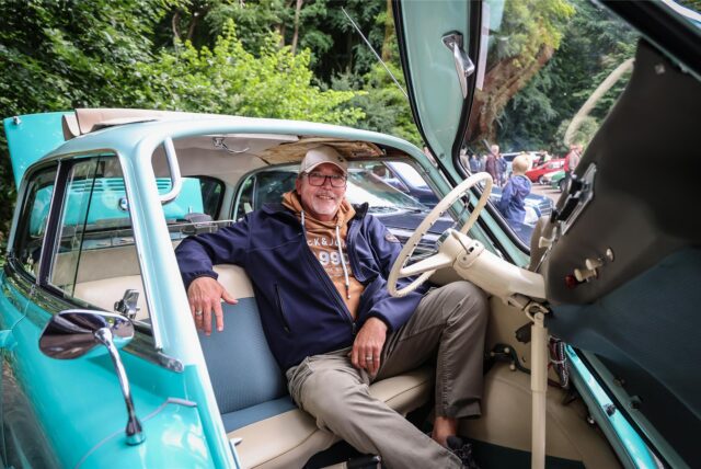 Ein Mann sitzt beim Oldtimer-Treffen bei Dieckmann’s in Dortmund-Syburg in einem alten, türkisfarbenen Auto.