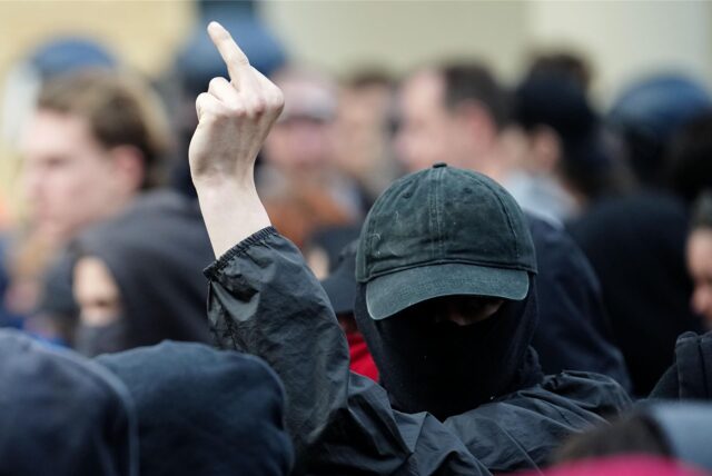 Ein Teilnehmer einer Demonstration aus dem linksextremen Spektrum zeigt den Mittelfinger.