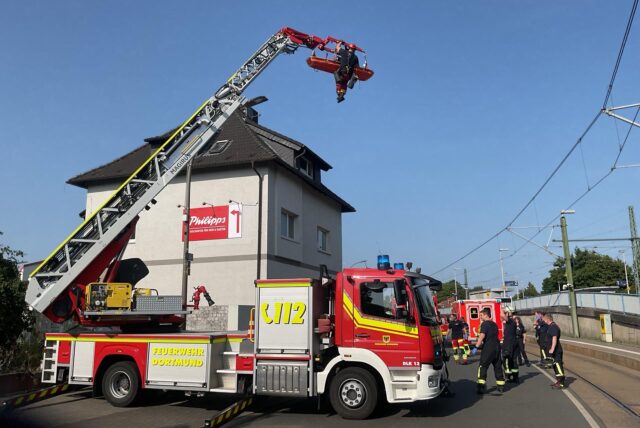 Höhenretter der Feuerwehr retten einen Mann mittels einer Drehleiter von einem Dach.