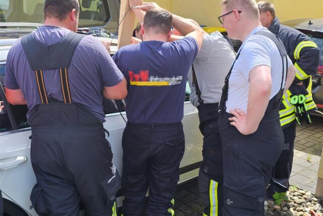 Ein Feuerwehrmann versucht durch einen Spalt den Schlüssel vom Beifahrersitz zu angeln.