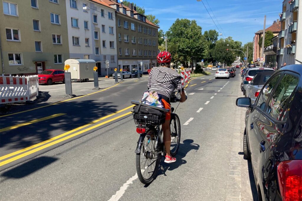Eine Radfahrerin fährt durch eine enge Baustellenführung. 