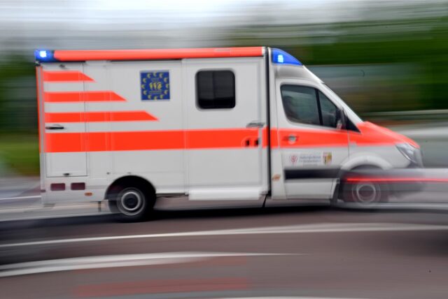 Ein Krankenwagen fährt mit Blaulicht über eine Straße.