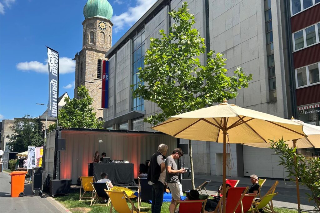Ein DJ-Container mit Liegestühlen vor der Kulisse der Reinoldikirche. 