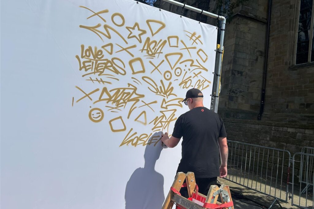 Ein Graffiti-Künstler sprayt auf eine große Leinwand.