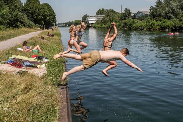 Mehrere Menschen springen an einem heißen Sommertag in den Dortmund-Ems-Kanal.