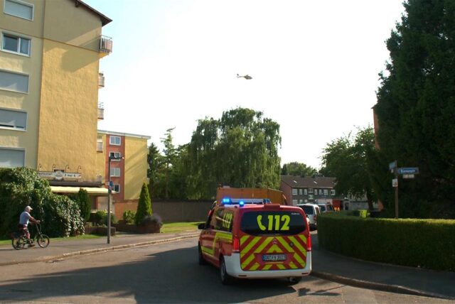 Vor einem Hochhaus in Dortmund-Asseln stehen mehrere Rettungsfahrzeuge der Feuerwehr. Im Hintergrund ist ein Hubschrauber am Himmel zu erkennen.