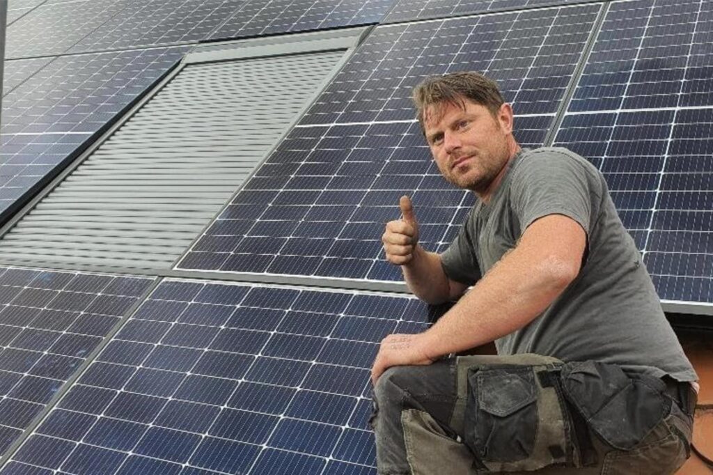 Niko Chatziliadis hält auf einem Dach mit PV-Anlage den Daumen nach oben.