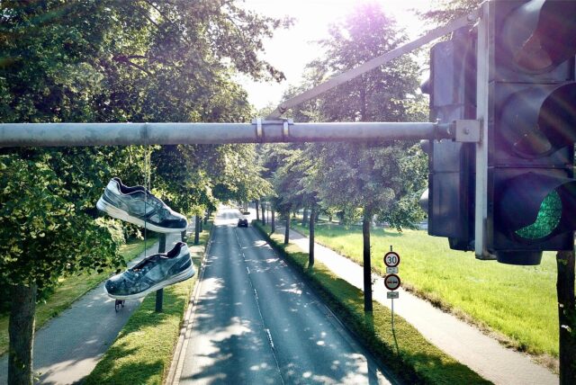 Ein an den Schnürsenkeln zusammengebundenes Paar Schuhe baumelt über einem Ampelmast am Bärenbruch in Kirchlinde.