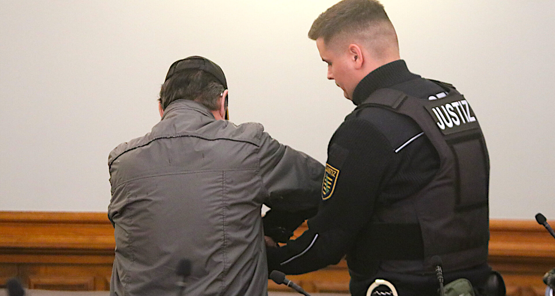 Angeklagter mit Justizbeamten im Gericht.