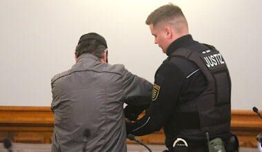 Angeklagter mit Justizbeamten im Gericht.