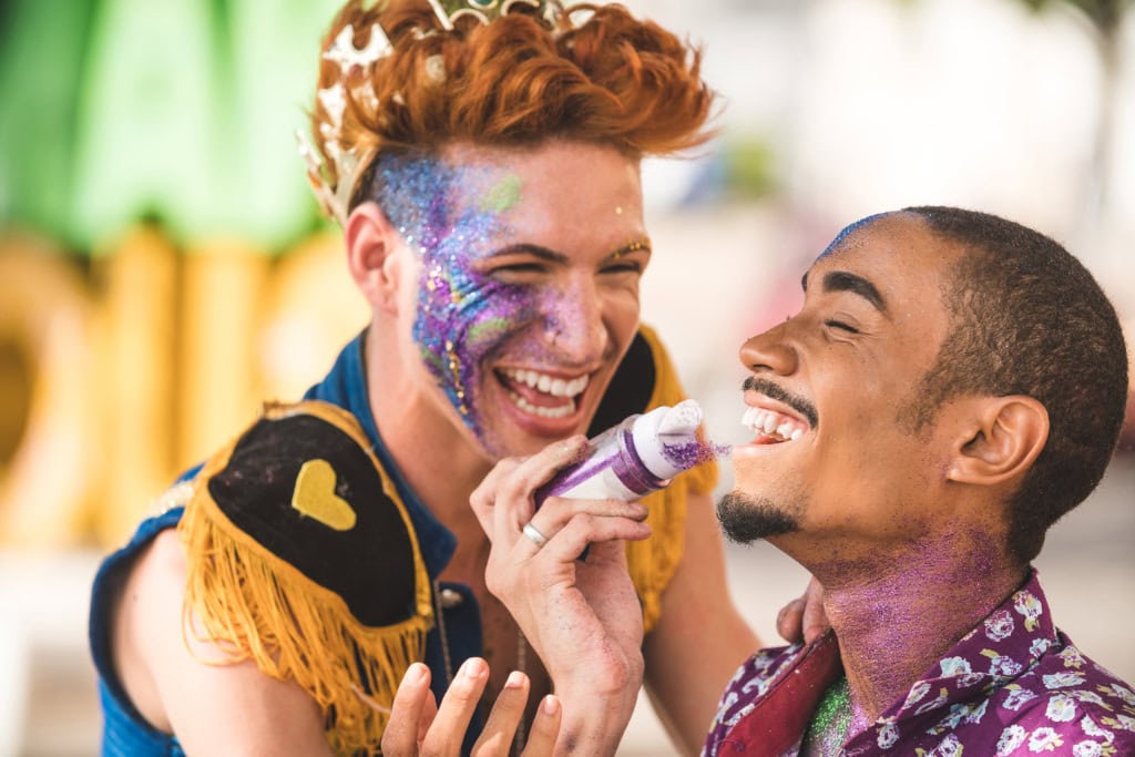 Zwei lachende Männer mit Glitzer im Gesicht feiern bunt geschminkt beim CSD Köln 2025.  