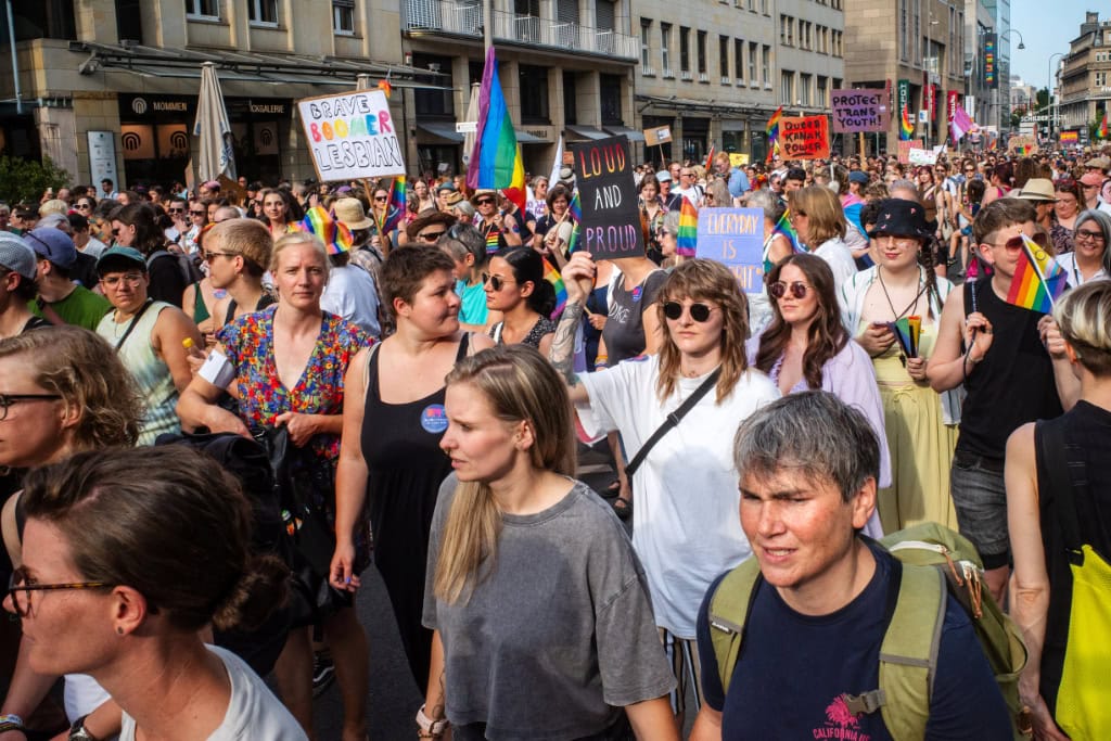 Menschenmenge beim Dyke March Köln 2025 mit Pride-Flaggen und feministischen Protestschildern.
