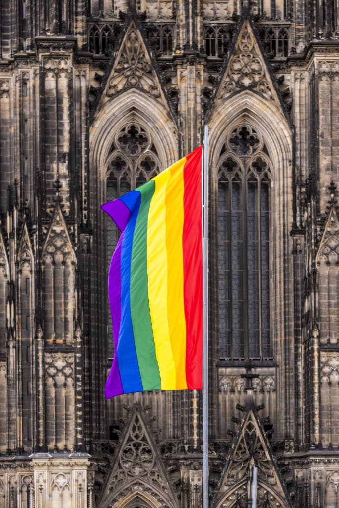 Regenbogenflagge weht vor dem gotischen Kölner Dom als Symbol für Vielfalt und LGBTQ+-Stolz.  