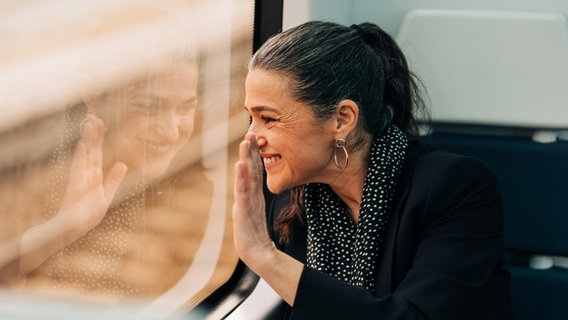 Frau winkt aus dem Zugfenster © picture alliance / Shotshop | Addictive Stock 