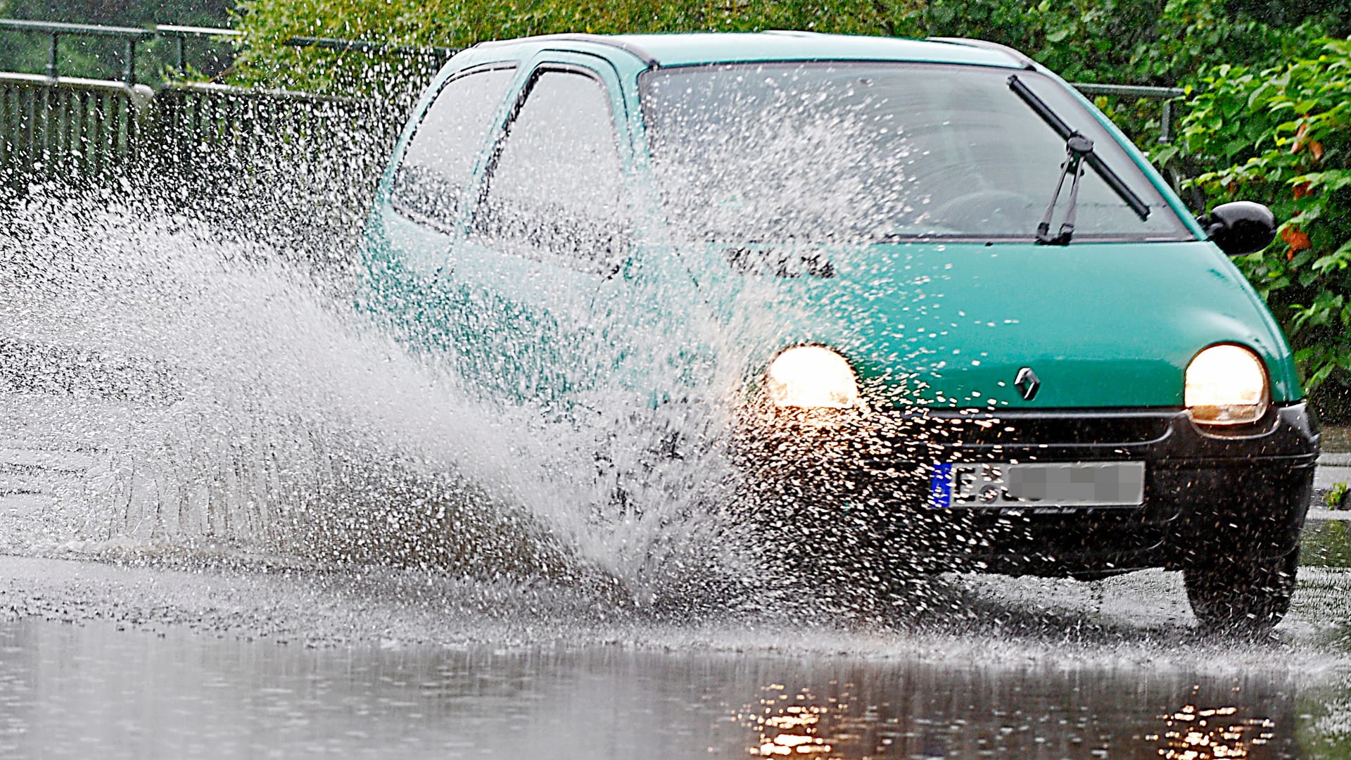 Auto pflügt durch eine Pfütze (Symbolfoto): Im Ruhrgebiet werden statt des mancherorts befürchteten Starkregens eher kleinere Schauer erwartet.