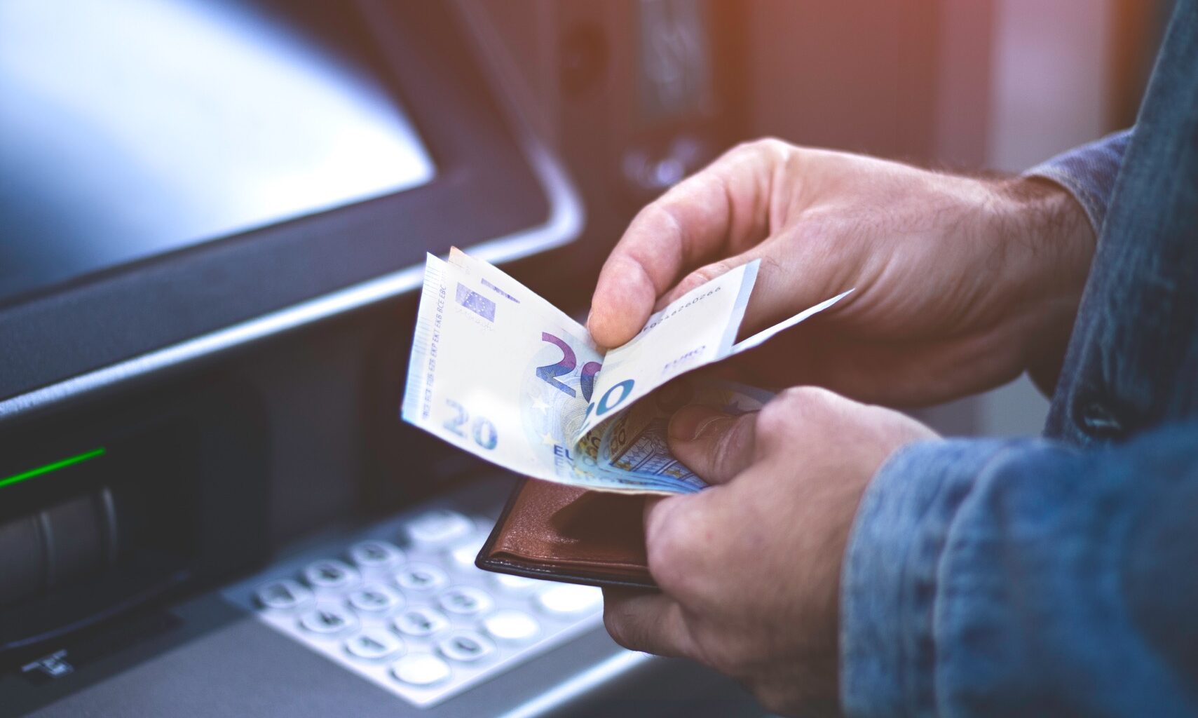 Mann hebt Geld am Automaten ab