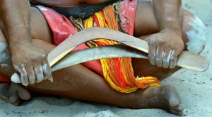 Aborigine hält zwei Bumerang-Varianten in der Hand