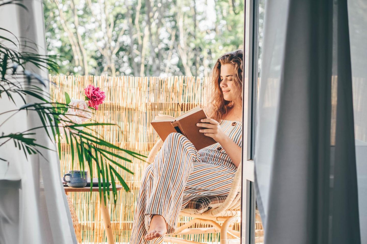 Frau liest auf dem Balkon | Bücher des Monats: Warum diese Bücher auf jede Sommer-Leseliste gehören