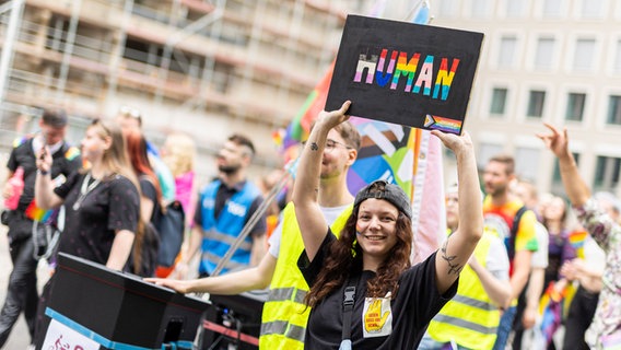 Hannover: Teilnehmer gehen beim Christopher Street Day (CSD) durch die Innenstadt. Eine Teilnehmerin hält ein Schild mit der Aufschrift "Human". © picture alliance/dpa Foto: Michael Matthey