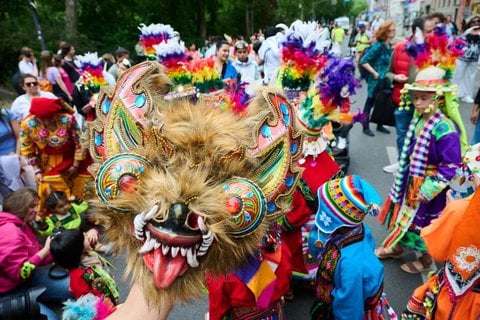 Kinder in traditionellen Kostümen tanzen am Mariannenplatz zur Musik.