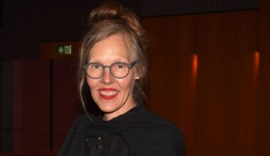 Porträt von Donata Wenders vor dunklem Hintergrund. Sie lacht in die Kamera.