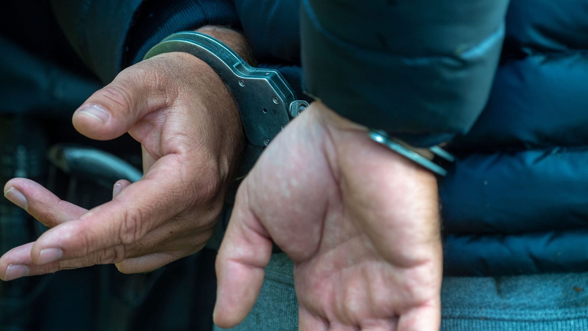Ein Mann trägt Handschellen (Symbolbild): Drogenfahndern gelang ein Schlag gegen den internationalen Drogenhandel.