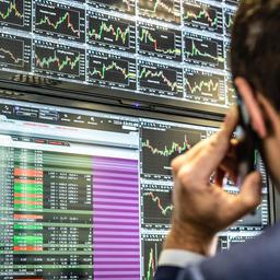 Börsenhändler vor Monitoren mit Kursverläufen.