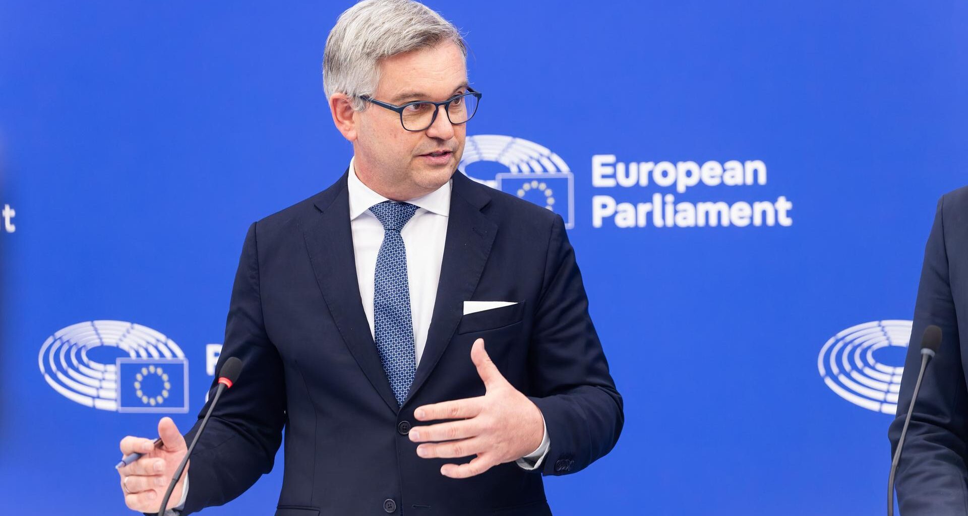 Brunner bei einem öffentlichen Auftritt im Europäischen Parlaments. Er spricht in ein Mikrofon und macht mit seinen Händen eine Geste.