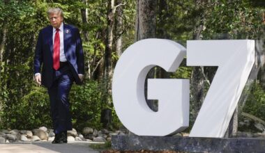 Ein Mann mit blauen Anzug läuft einen Weg entlang. Es ist US-Präsident Donald Trump. Neben ihm ist ein weißes G und eine Sieben.