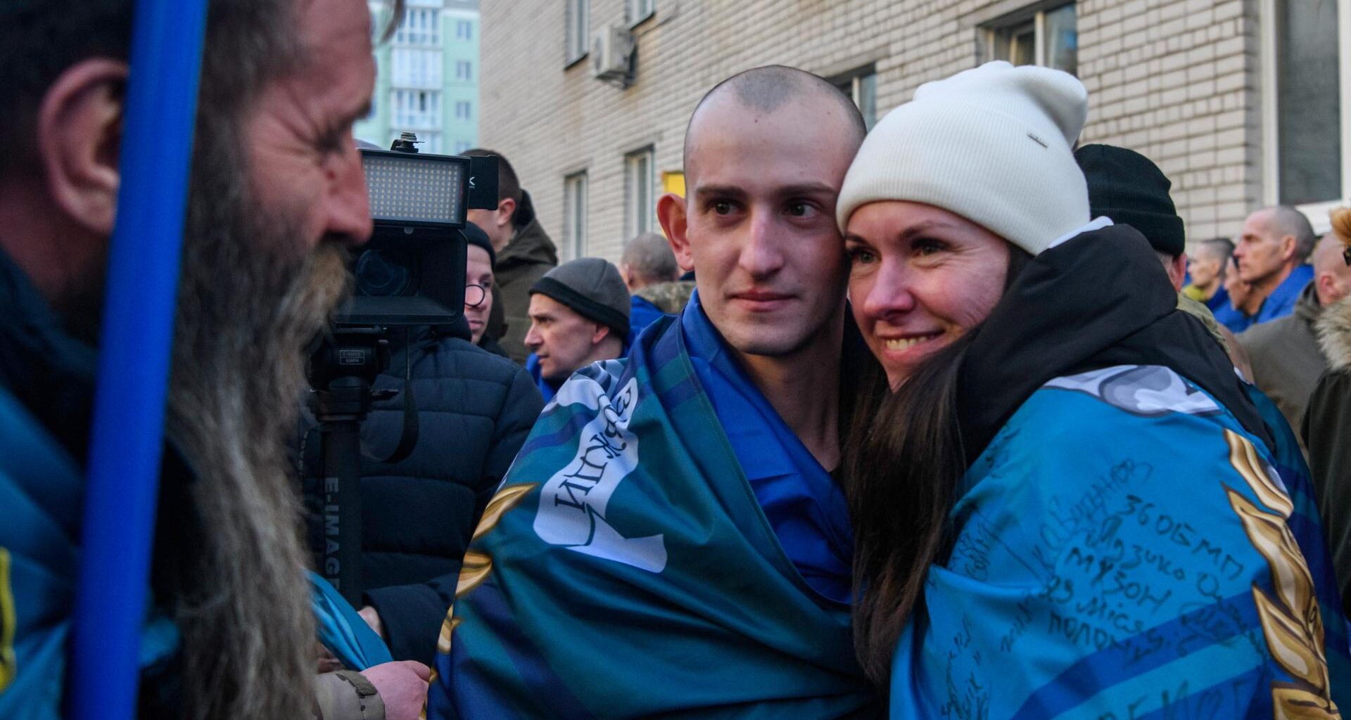 Ein Mann und eine Frau umarmen sich und blicken in die Kamera im Rahmen eines Gefangenenaustauschs zwischen Russland und Ukraine