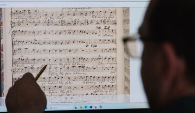 Ein Mann sitzt vor einen Computerbildschirm. Er zeigt mit einem Stift darauf. Zu sehen sind gescannte Partituren von Georg-Friedrich-Händel.
