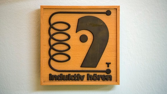 Ein Hinweisschild "induktiv hören" hängt vor einem Konzertsaal. © picture alliance / dpa | Rolf Vennenbernd 