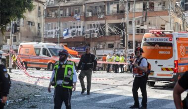 Rettungskräfte stehen vor einem stark beschädigten Gebäude, ein Teil des vorgelagerten Platzes ist abgesperrt.