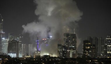 Es ist Nacht. Man sieht Gebäude und die Lichter Tel Avivs aus der Ferne. Dichter grauer Rauch steigt über Häusern auf.