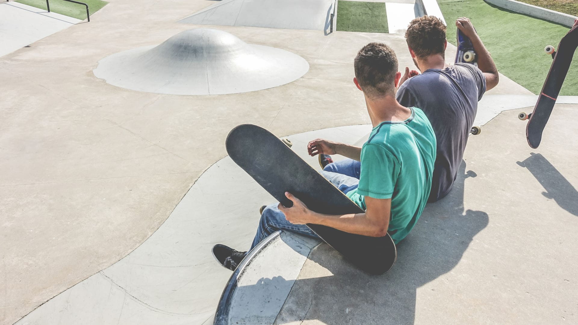 Teenagers performing with skateboard in city skate park - Young skaters doing tricks and skills outdoor - Extreme sport, youth lifestyle and friendship concept - Focus on close-up guy