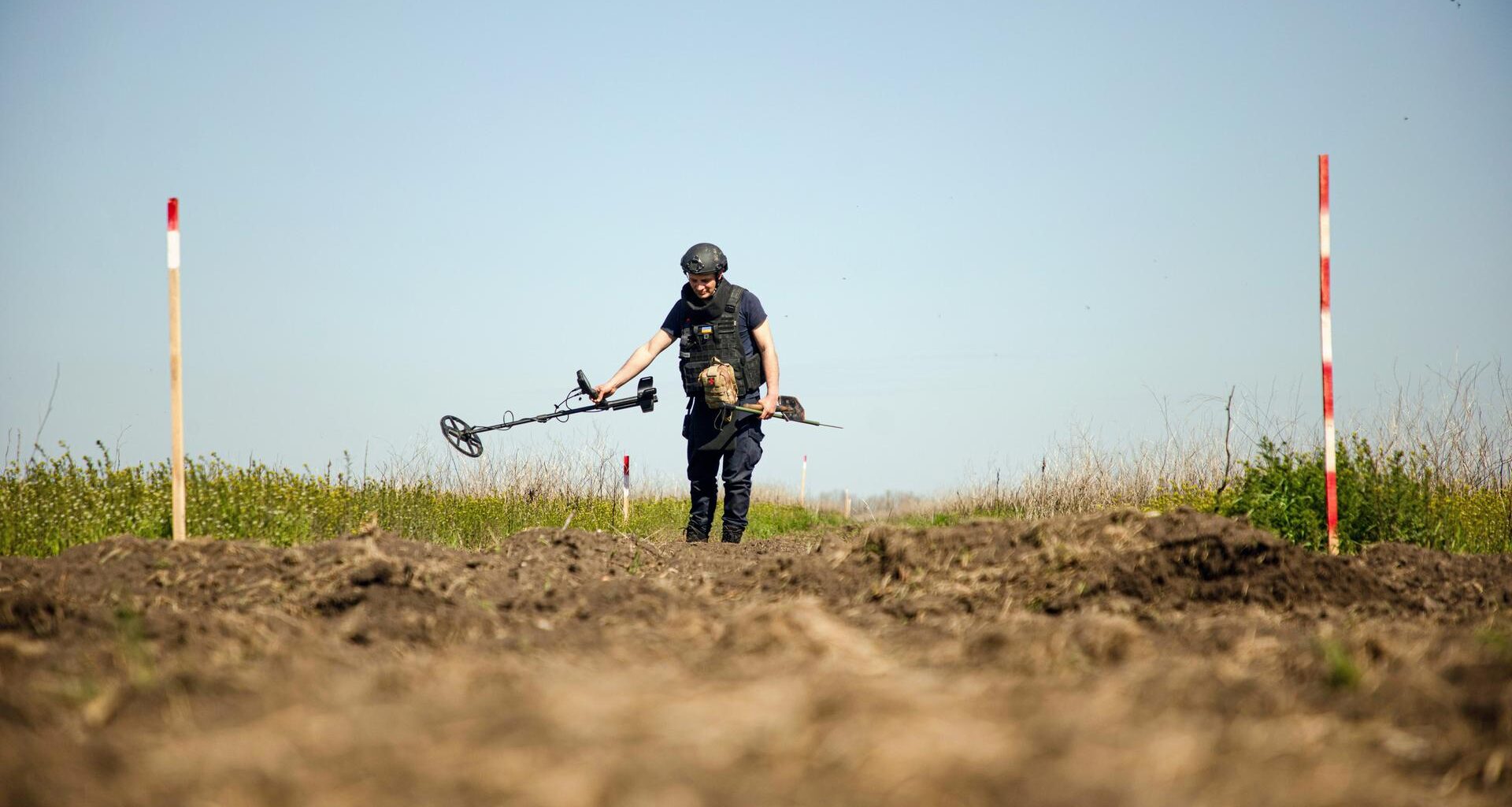 Eine Person von einem Minenräumkommando tastet den Boden während einer Minenräummission in der Region Mykolajiw (Ukraine) am 17. April 2025 mit einem Metalldetektor ab.