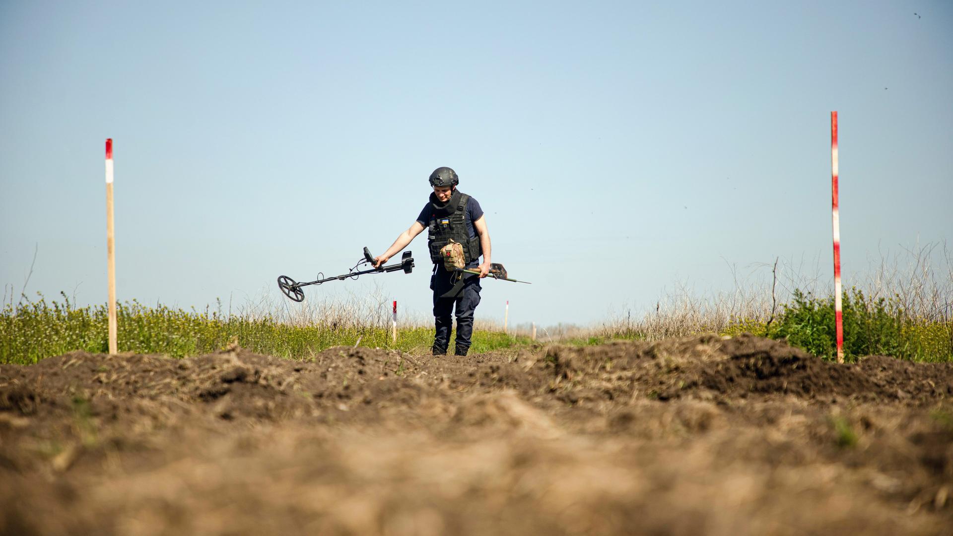 Eine Person von einem Minenräumkommando tastet den Boden während einer Minenräummission in der Region Mykolajiw (Ukraine) am 17. April 2025 mit einem Metalldetektor ab. 