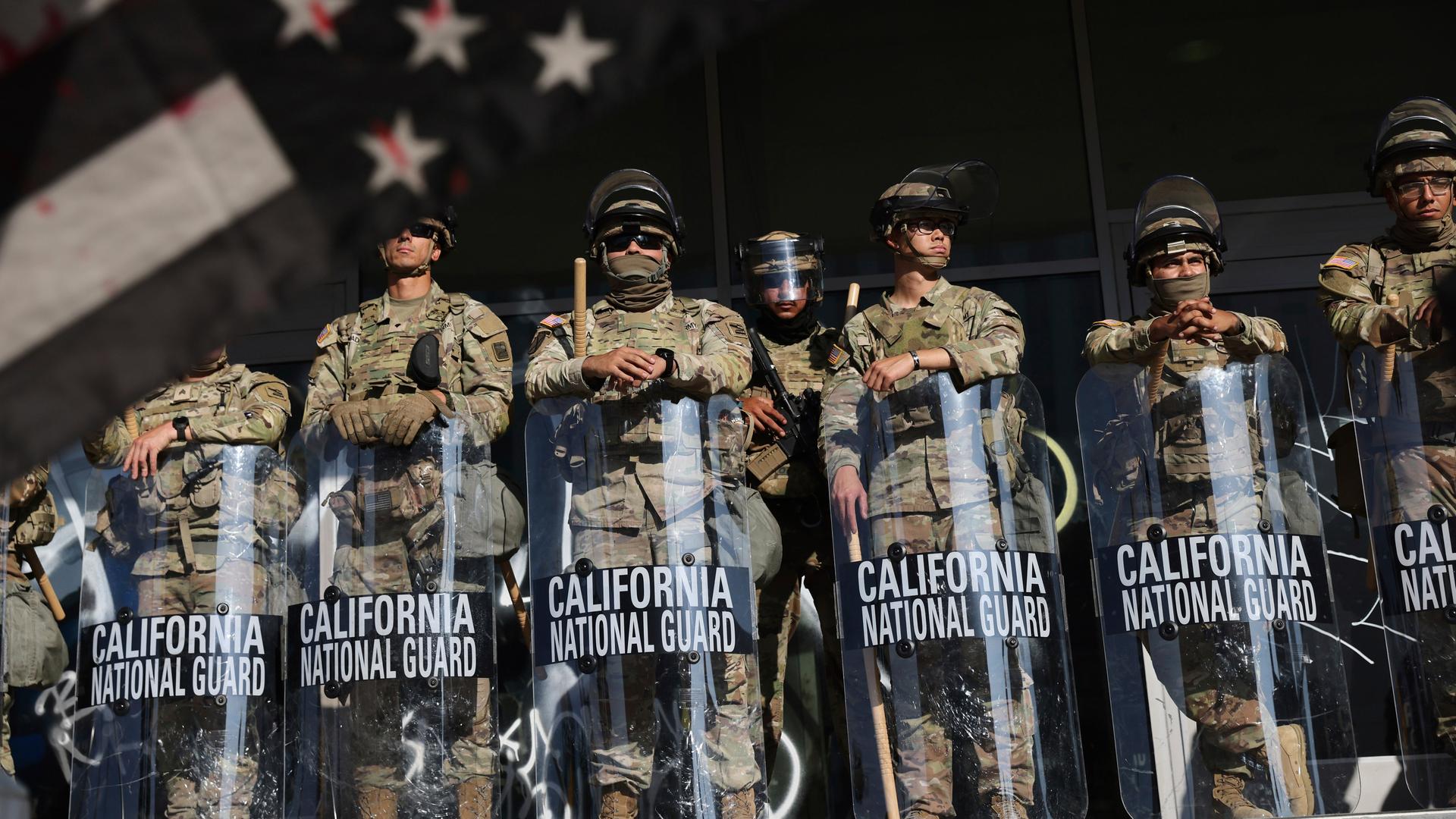 Soldaten der Nationalgarde sind während Protesten als Reaktion auf eine Reihe von Razzien der Einwanderungs- und Zollbehörde der Vereinigten Staaten (ICE) im ganzen Land in der Nähe eines Eingangs zu einem Bundesgebäude in Los Angeles postiert.