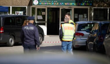 22.05.2025, Berlin: Polizisten stehen vor einer Schule im Berliner Bezirk Spandau, an der es am Vormittag einen möglichen Messerangriff auf einen Schüler gab.