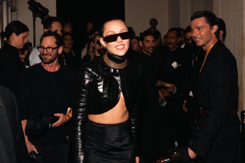 Miley Cyrus posiert auf Met Gala 2025 für Fotograf:innen, während Patrick Schwarzenegger zusieht