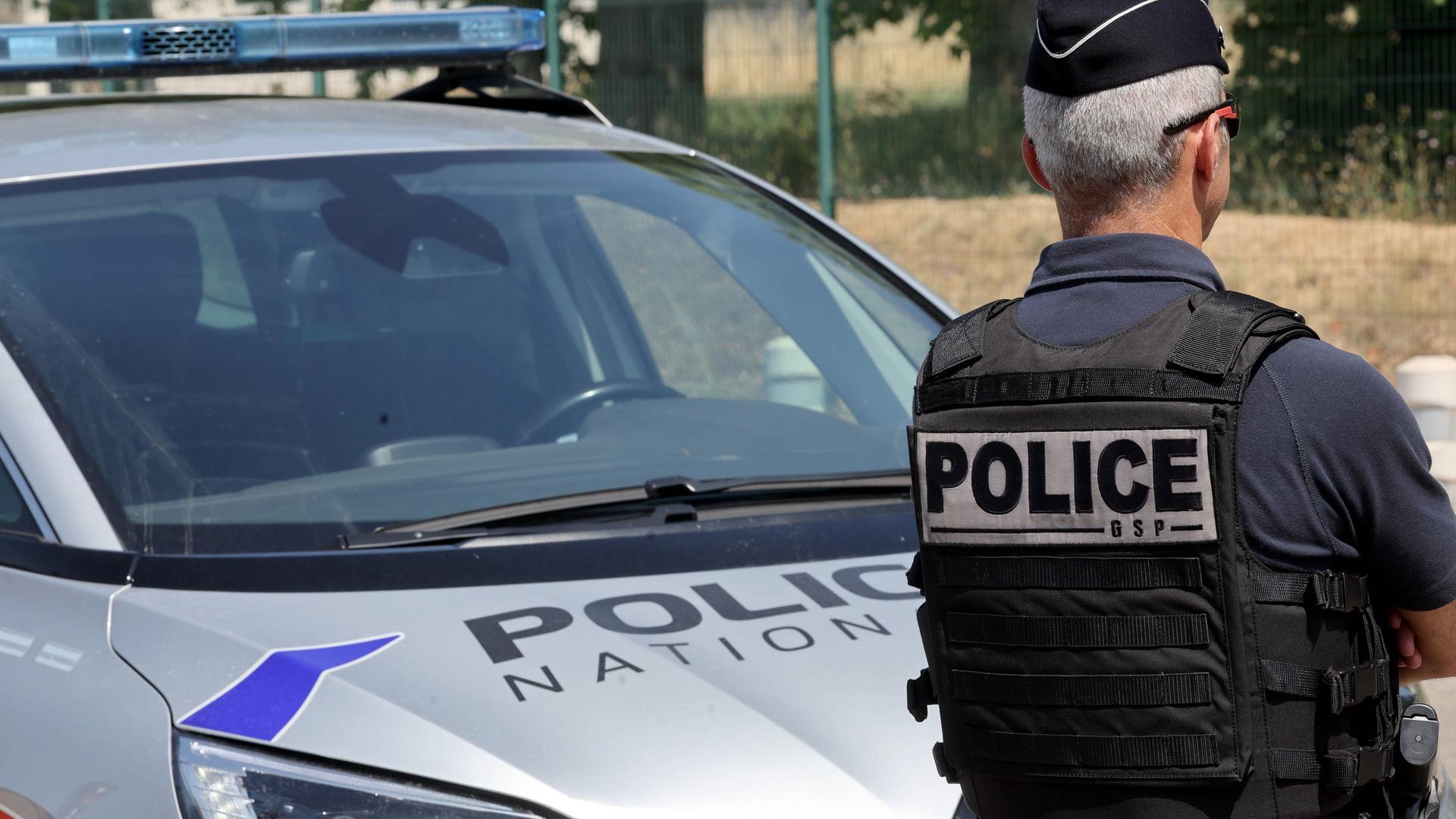 französischer Polizist vor Polizeiauto 