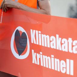 Symbolbild:Eine Person mit orangener Warnweste hält ein Transparent mit der Aufschrift "Klimakatastrophe ist kriminell" in den Händen.(Quelle:picture alliance/dpa/F.Sommer)